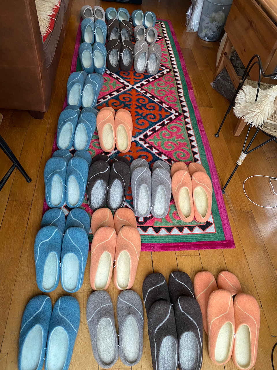 Handmade felt slippers in many colours, laid out on a Kyrgyz shyrdak carpet